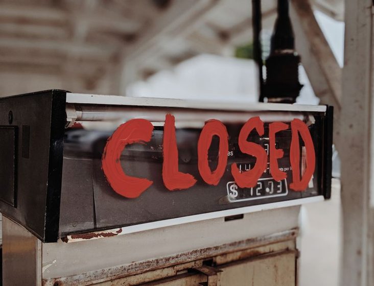 Weathered enamel sign on a steel panel above a storefront