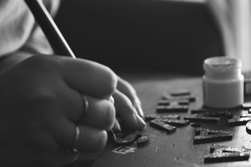 A sign painter applying gold leaf lettering to a black fascia board